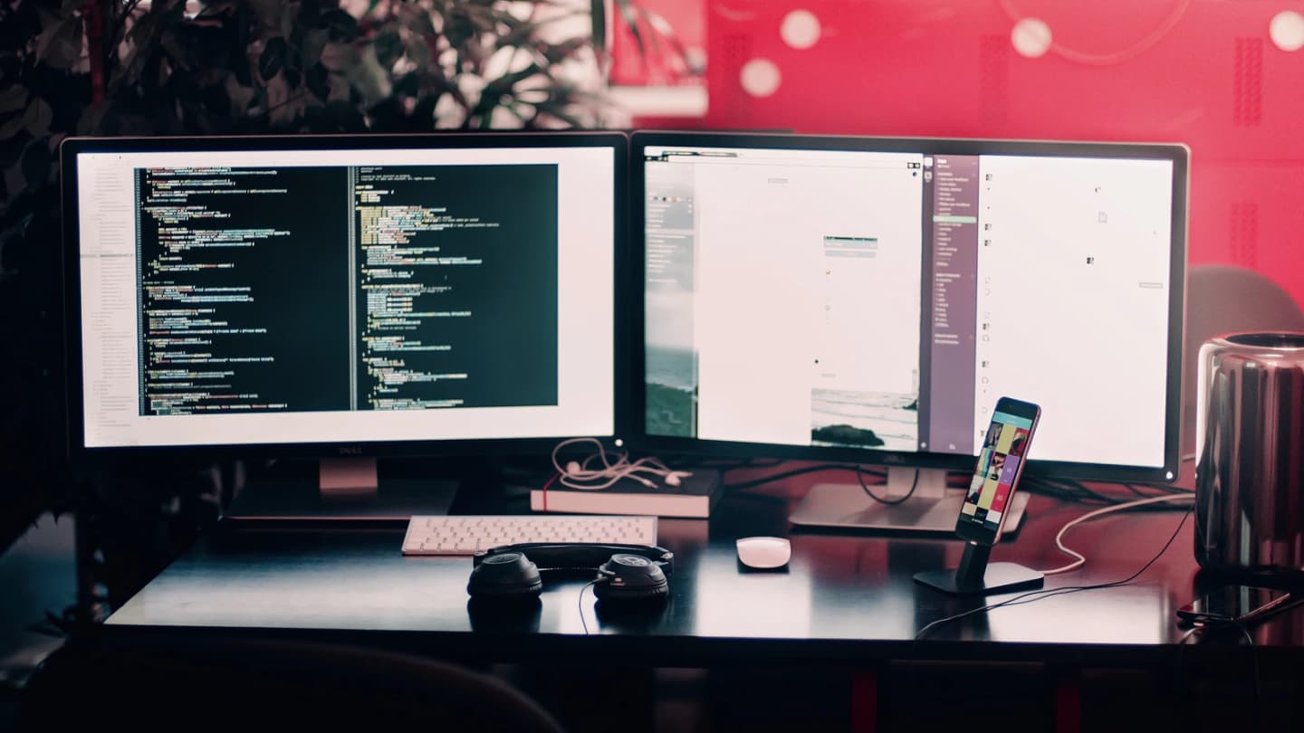 Dual-monitor coding workstation representing Grok 4.6 and long-running AI agents
