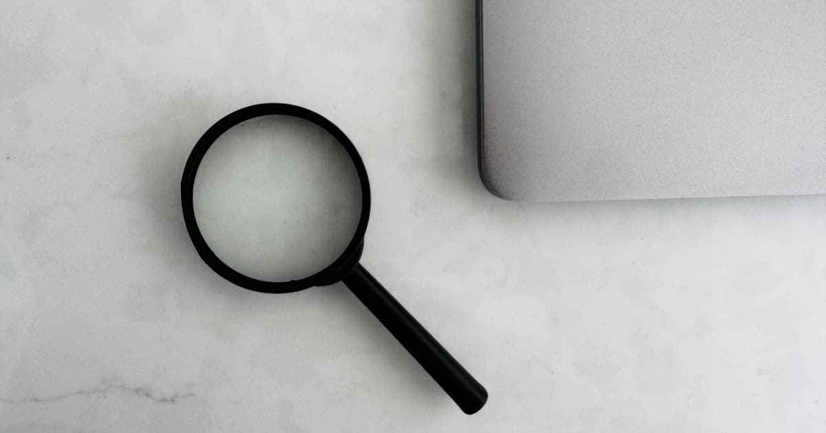A magnifying glass beside a laptop representing image verification